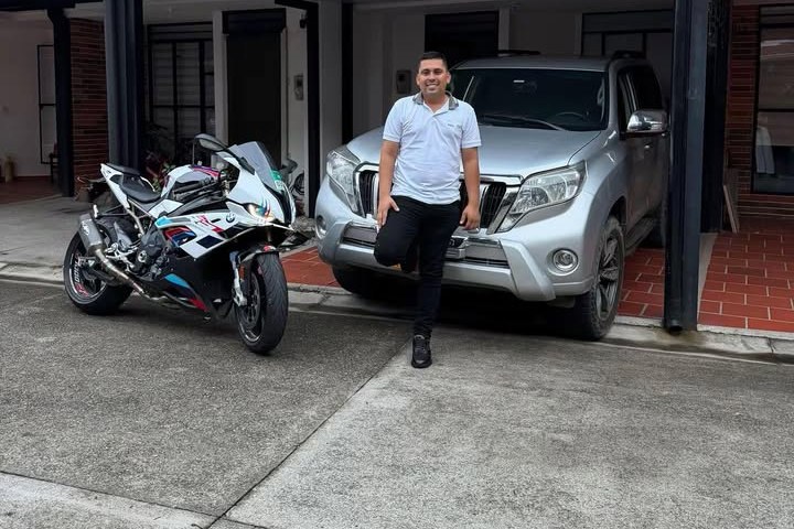 Jhonatan Sánchez junto a una camioneta Toyota Prado y una moto BMW